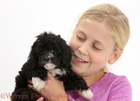 Girl cuddling black Cavapoo puppy