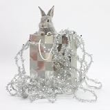 Two baby silver rabbits in a gift bag with Christmas tinsel