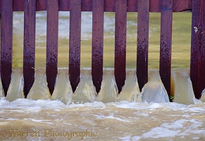 Flood water pouring through a fence