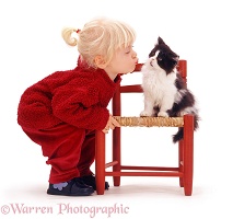 Little girl kissing a black-and-white kitten