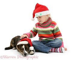 Girl and puppy both wearing Santa hats