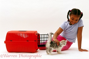 Girl putting kitten in a cat carrier